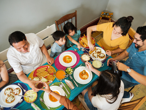High angle view of a mexican family eating together at a colorful table with tasty mexican food.