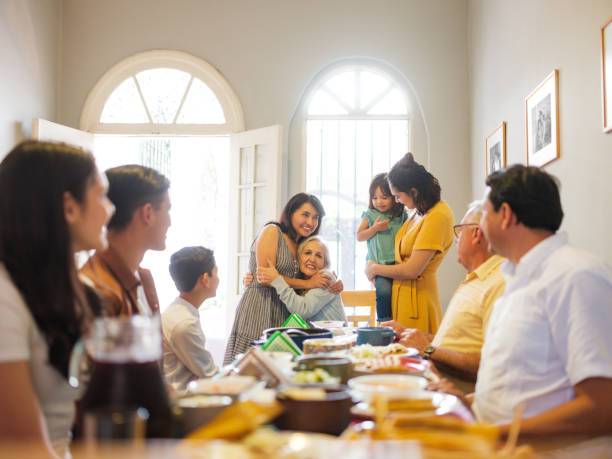 Mexican family at lunch table embracing grandmother A mexican family eating lunch at the table and taking turns to stand up and embracing grandmother. family reunion stock pictures, royalty-free photos & images