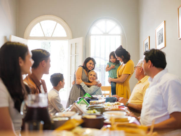 Mexican family at lunch table embracing grandmother A mexican family eating lunch at the table and taking turns to stand up and embracing grandmother. family reunion celebration stock pictures, royalty-free photos & images