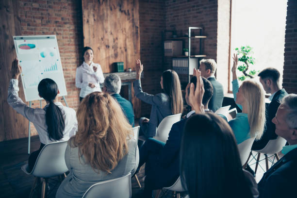 crowd of stylish elegant sharks attending educative event sitting listening to coacher speaker top financier economist about growth strategy salary profit at industrial loft style interior work place station - question mark audio imagens e fotografias de stock