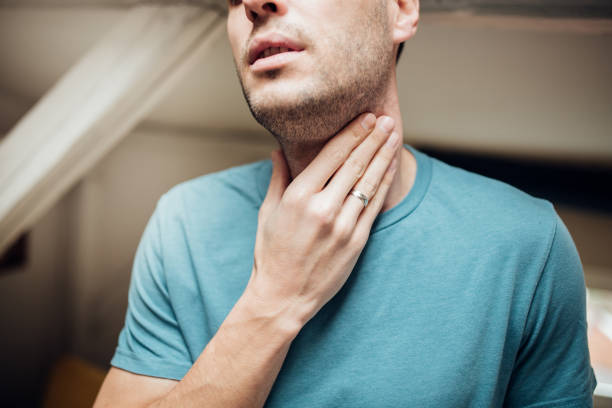 Man touching his throat Young man with a sore throat man fever stock pictures, royalty-free photos & images