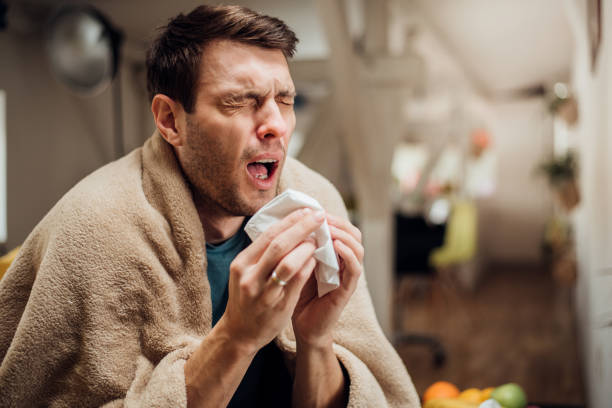 Ill man sneezing Sick young man coughing and sneezing sneezing stock pictures, royalty-free photos & images