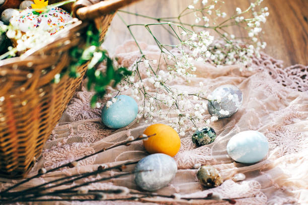 istock Stylish Easter eggs at easter bread cake, ham, beets, sausage, butter, green branches in wicker basket on rustic fabric with spring flowers. Happy Easter, holiday traditional feast. Top view 1137361415