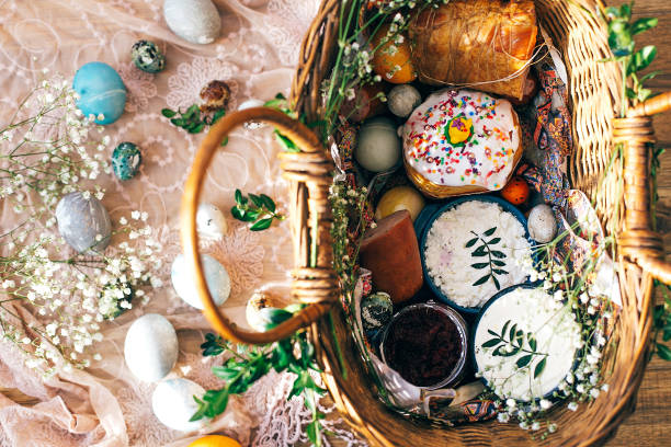 istock Stylish Easter basket with modern eggs, easter bread cake, ham, beets, sausage, butter and green branches on rustic fabric with spring flowers in sunny light. Flat lay. Happy Easter concept 1137361652