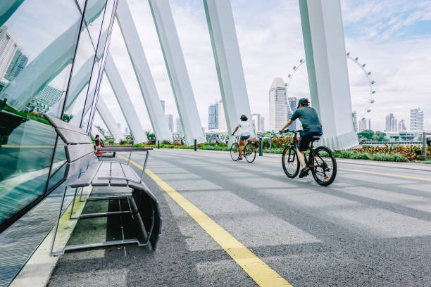 湾、フラワードームシンガポールによる公園の庭での建物で速いサイクリストを移動します。 - built structure building exterior facade office building ストックフォトと画像