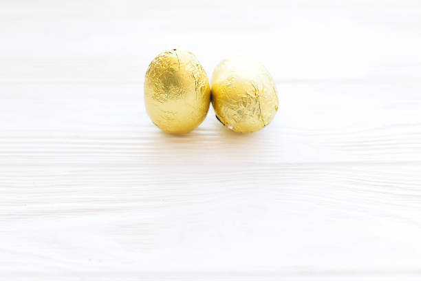 istock Stylish Easter eggs in golden foil on white wooden background with space for text. Modern chocolate gold easter eggs. Happy Easter. Greeting card. Holiday gift 1137363982