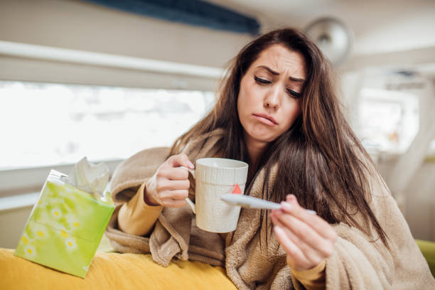 istock Girl holding tea mug when looking at thermometer 1137364535