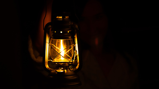 Somebody is holding a classic kerosene lamp during night (totally dark area)