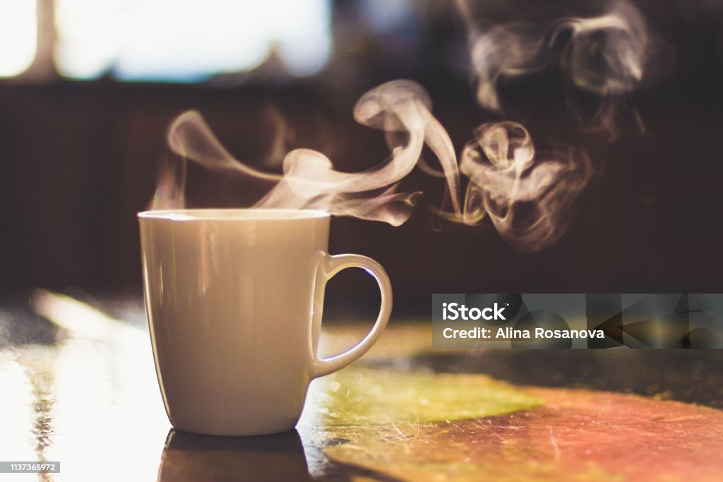 Close up of steaming cup of coffee or tea on vintage table - early morning breakfast on rustic background Cup of hot drink on the table Coffee - Drink Stock Photo