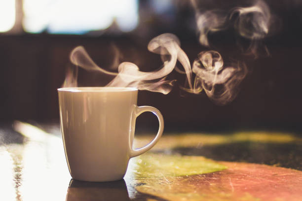 Close up of steaming cup of coffee or tea on vintage table - early morning breakfast on rustic background stock photo
