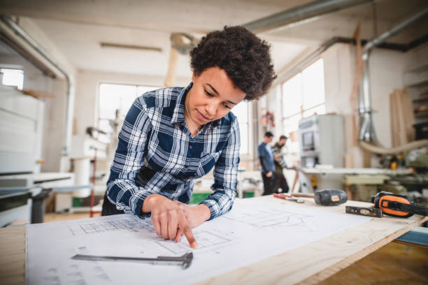 istock Young woman working on a blueprint in the workshop 1137368208