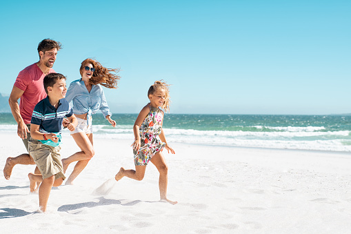 Familia feliz corriendo en la playa photo