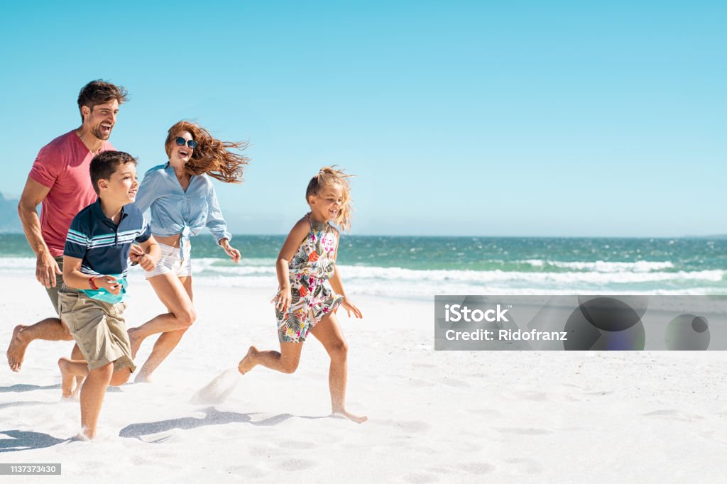 Famille heureuse exécutant sur la plage - Photo de Famille libre de droits