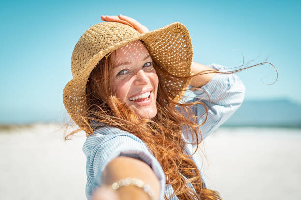 uśmiechnięta dojrzała kobieta ze słomkowym kapeluszem - enjoyment people beach sun protection zdjęcia i obrazy z banku zdjęć