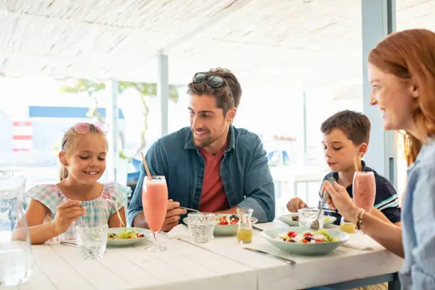 Photo of Happy young family enjoying lunch outdoor