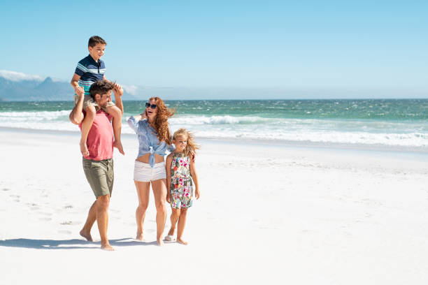 familia caminando en la playa - family with two children father clothing smiling fotografías e imágenes de stock