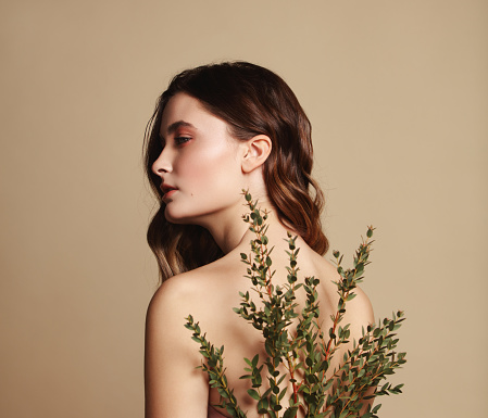 Portrait of beautiful and fresh girl with plant behind her back