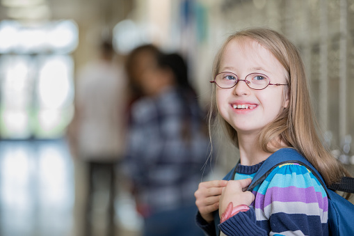Beautiful junior high school student with Down Syndrome smiles on her way to class