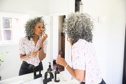 A beautiful black woman puts on her makeup in a bathroom