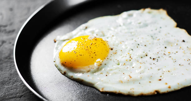 istock Fried egg in a iron frying pan on Dark grey black slate background 1137392217