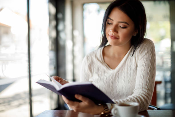 istock Young woman reading a book at a cafe 1137393248