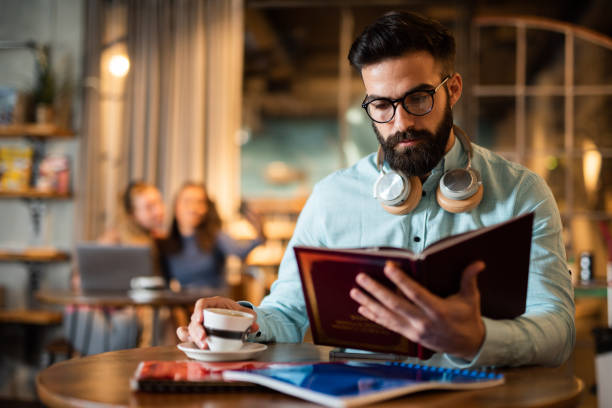 Male student drinking coffee and reading a book.