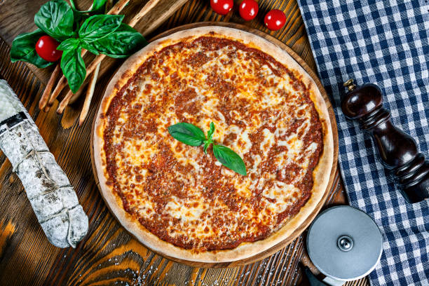 Top view on homemade italian pizza with bolognese. Pizza on rustic wooden background with tomato, salami, basilic. Copy space. Traditional italian cuisine. stock photo