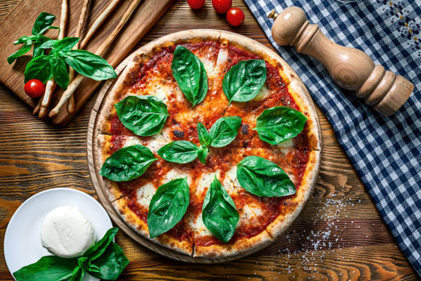 Top view on homemade italian margarita pizza. Pizza on rustic wooden background with tomato, Mozzarella, basilic. Copy space. Traditional italian cuisine. stock photo