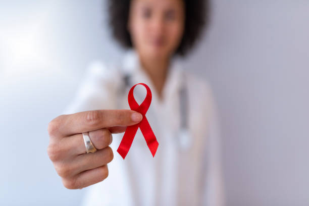 Doctor Hands Holding Red Cancer Awareness Ribbon Red ribbon for cancer awareness. Support people living with tumor illness. Doctor Hands Holding Red Cancer Awareness Ribbon. Concept of medicine oncology closeup world aids day stock pictures, royalty-free photos & images