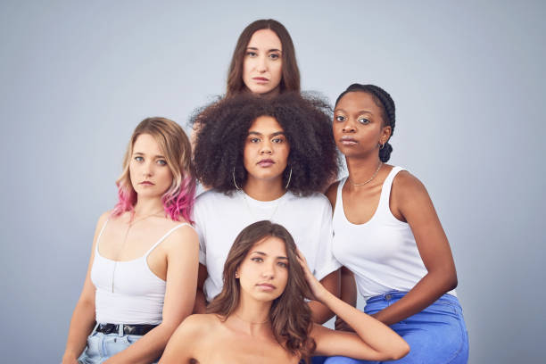 Studio shot of a group of attractive young women posing together against a gray background