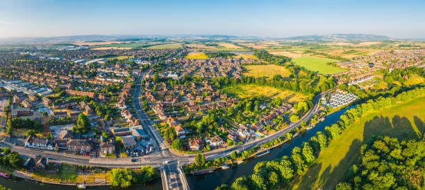 Aerial panorama over suburban family homes surround by green fields Panoramic aerial view over a country town, riverside homes and suburban streets surrounded by pasture, crop fields and farmland. english culture photos stock pictures, royalty-free photos & images