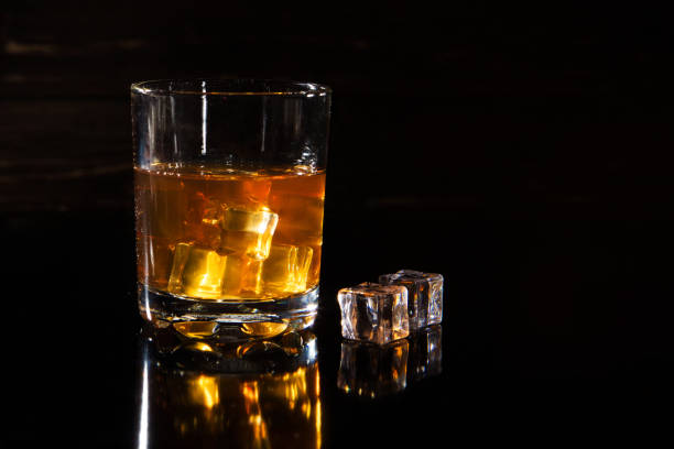 istock Glass of whiskey with ice on black background 1137406887