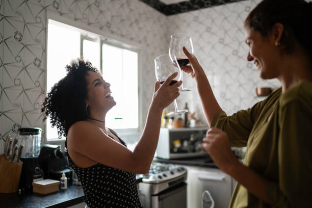 lesbische koppel op feestelijke toast in kitchen - drinking wine stockfoto's en -beelden