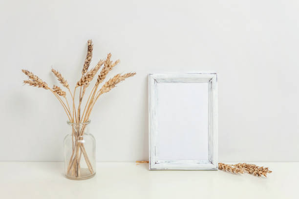 istock Vertical frame mockup with wild rye bouquet in glass vase near white wall 1137408401
