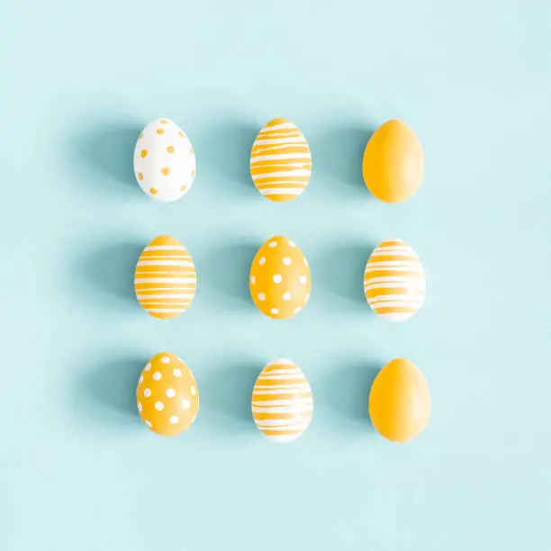 Photo of Easter composition. Easter eggs on pastel blue background. Flat lay, top view, square