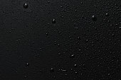 Black surface with clear water drops, background