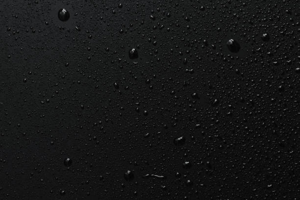 Black surface with clear water drops, background Close-up of raindrops on black rough surface, dark background Wet stock pictures, royalty-free photos & images