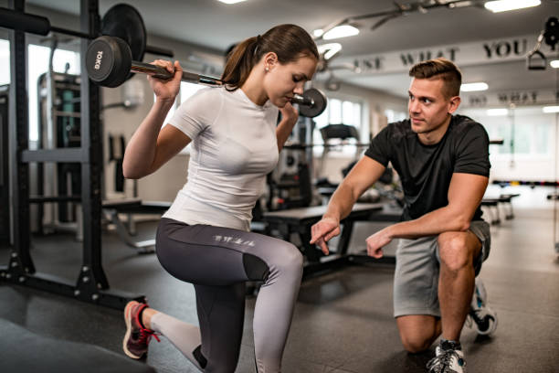 Fitness Instructor Guiding Young Woman When She Exercises Fitness Instructor Guiding Young Woman When She Exercises. casarsaguru stock pictures, royalty-free photos & images