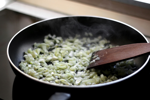 Frying onion on a pan with olive oil. Selective focus.