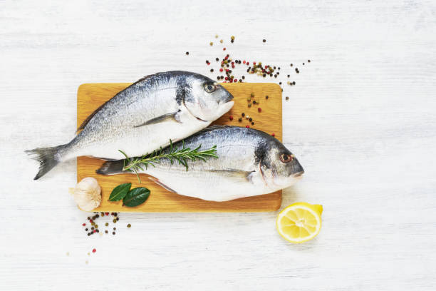 raw dorada fish with spices on wooden cutting board. healthy food concept. top view, copy space. - fish spice imagens e fotografias de stock