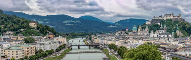 panoramablick auf salzburg und salzach auf cloudy sky - kollegienkirche stock-fotos und bilder