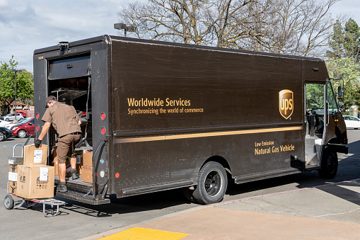 Davis, CA, USA 03/20/2019 - UPS delivery vehicle and busy worker in the city of Davis, CA. UPS is one of the largest package company headquartered in Sandy Springs, Georgia.