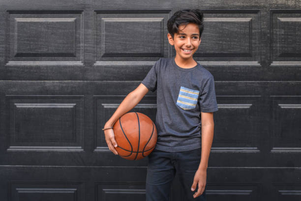 istock Boy holding basketball against wall 1137444167
