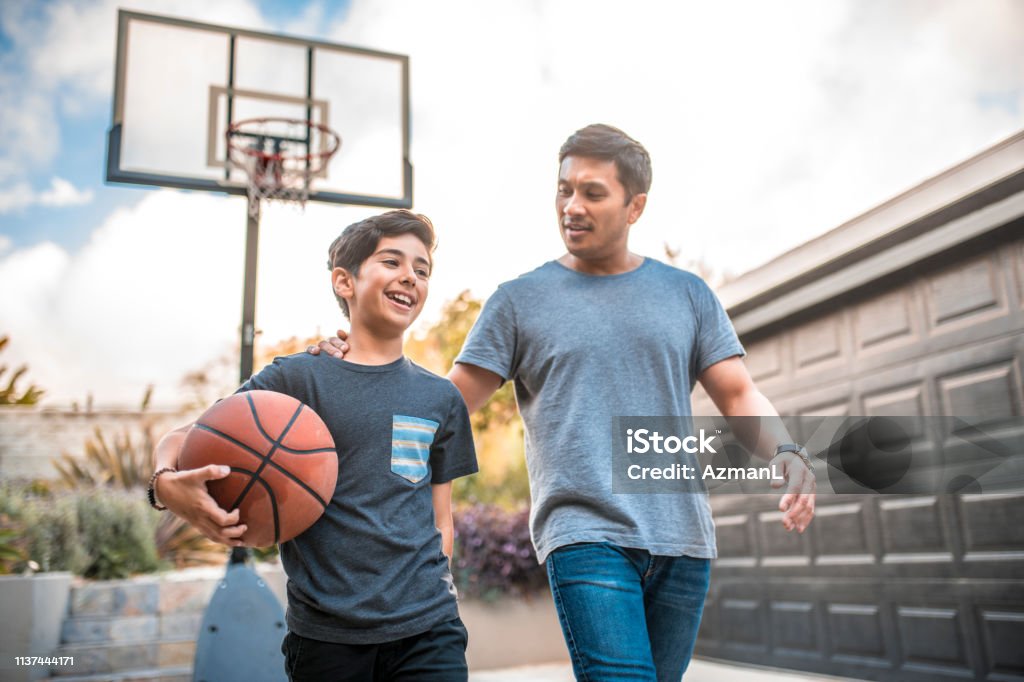 Father and son after the basketball match on back yard Happy boy after the  basketball match with his father. Mid adult man and child are smiling in backyard. They are wearing casuals during weekend. Father Stock Photo