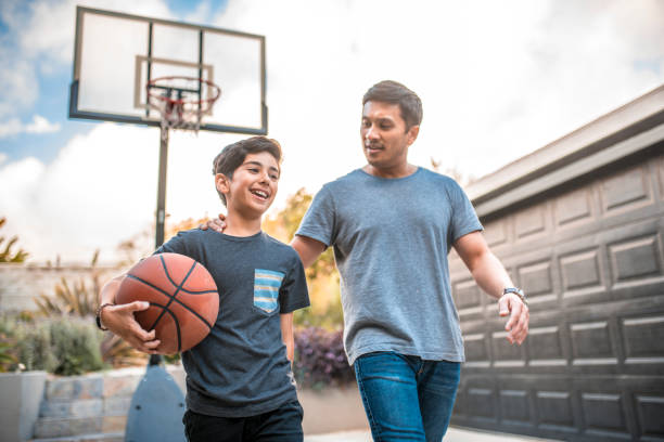 pai e filho após o fósforo de basquetebol na jarda traseira - adult hobbies horizontal photography - fotografias e filmes do acervo