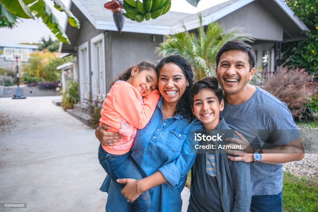 Portrait of happy family against house Portrait of happy family against house. Multi-ethnic parents and children are smiling on driveway. They are having fun together during weekend. Family Stock Photo