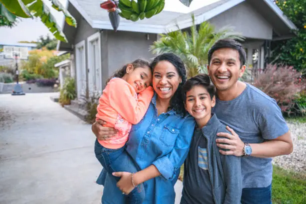 Portrait of happy family against house. Multi-ethnic parents and children are smiling on driveway. They are having fun together during weekend.
