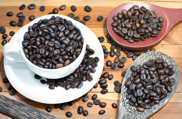 istock Dark roasted coffee beans with white cup and wooden spoon. 1137458527