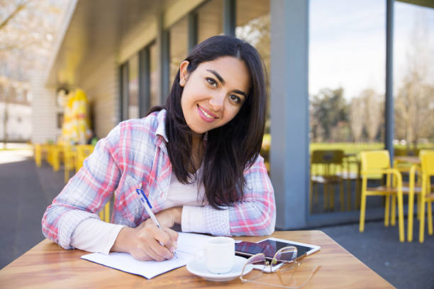istock Happy woman making notes in outdoor cafe 1137462926