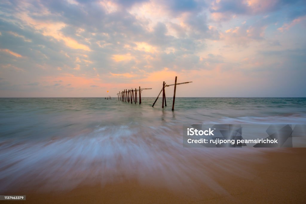 The old and broken wooden bridge The old and broken wooden bridge on the beach with sunset Beauty In Nature Stock Photo